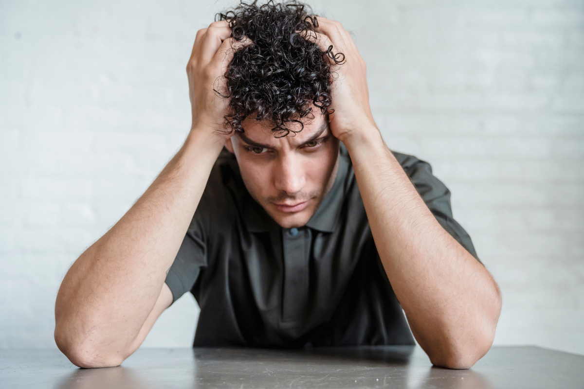 Young Upset Man Sitting Holding His Head in Hands 