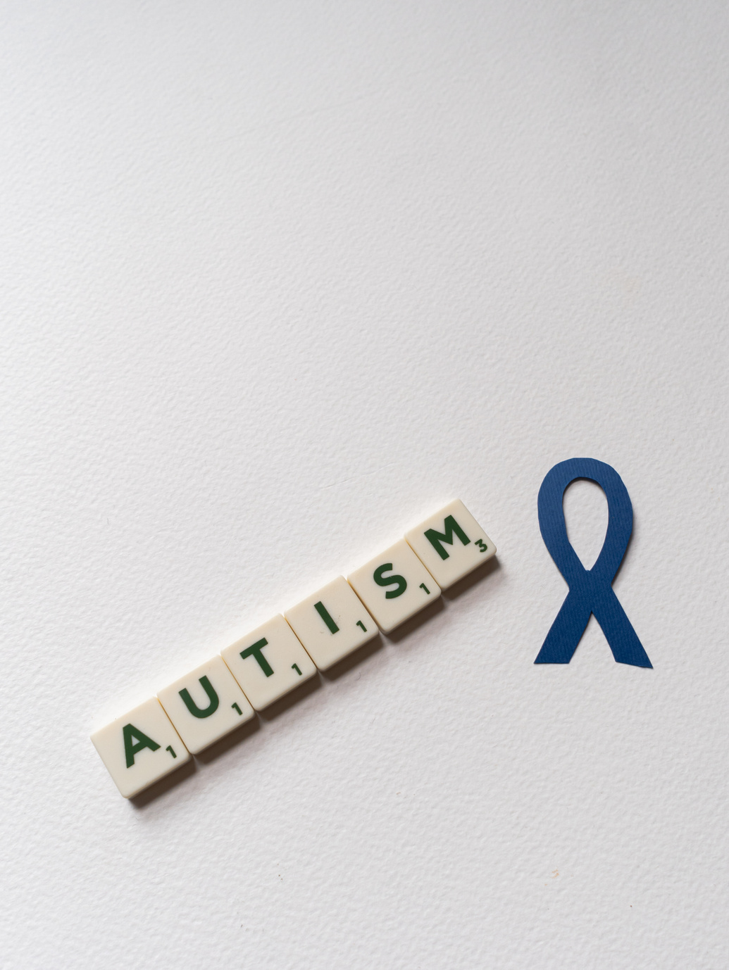  Blue Autism Awareness Ribbon and Scrabble Tiles on White Background